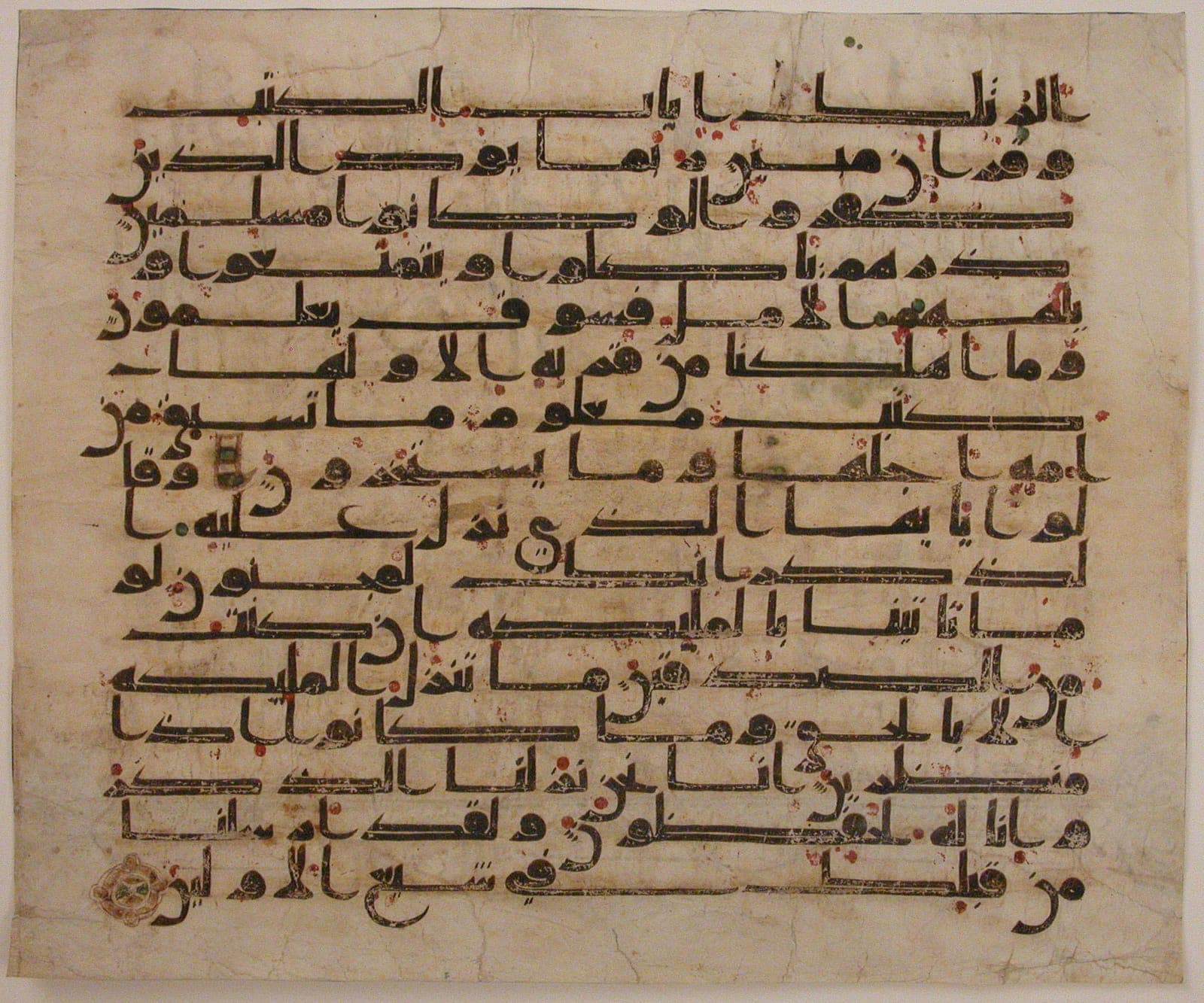 Eighth-century Qur’an folio in Kufic script on parchment, with red vowel dots and a gold verse marker.