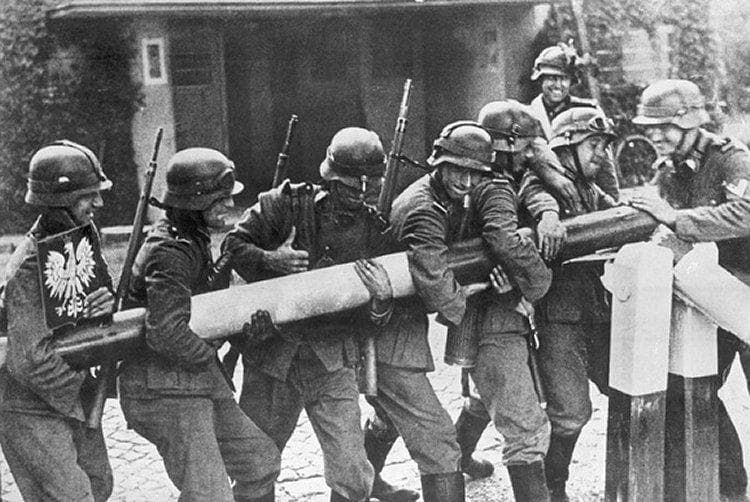 German soldiers lifting a border barrier painted with the Polish white eagle.