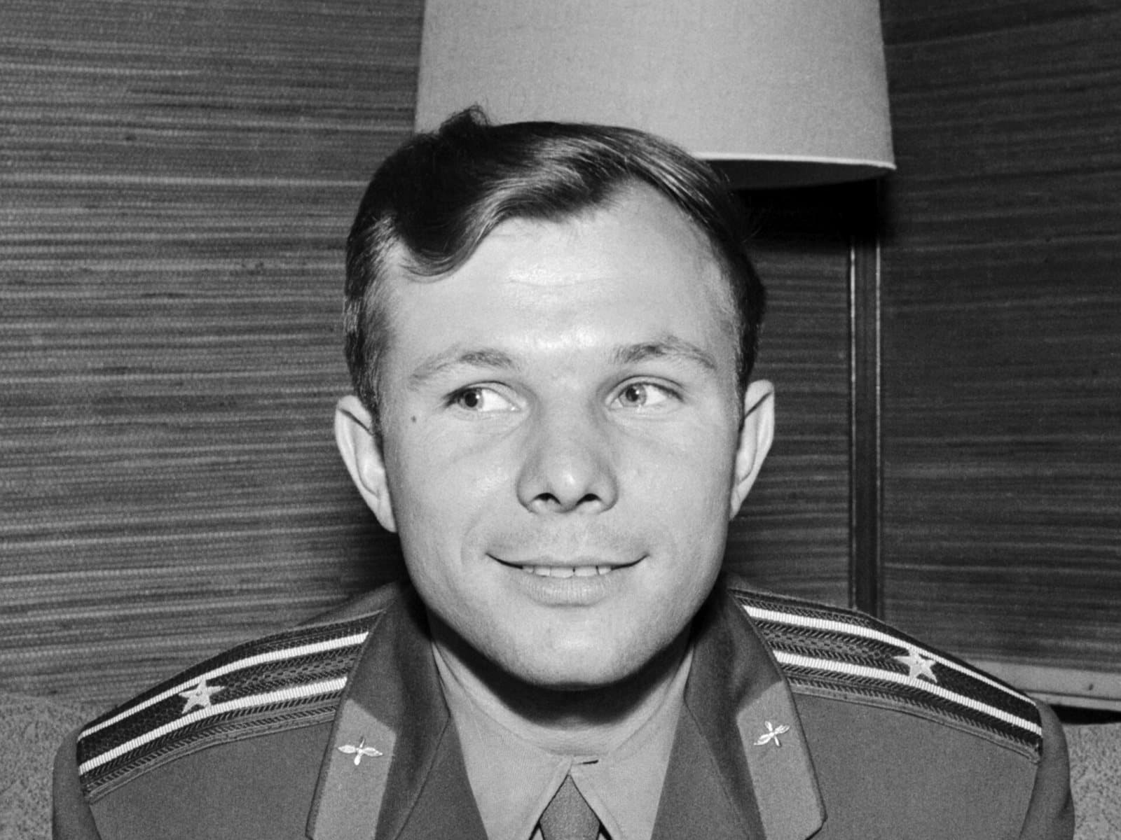 Black-and-white portrait of Yuri Gagarin in uniform, smiling, at a press conference in Finland.