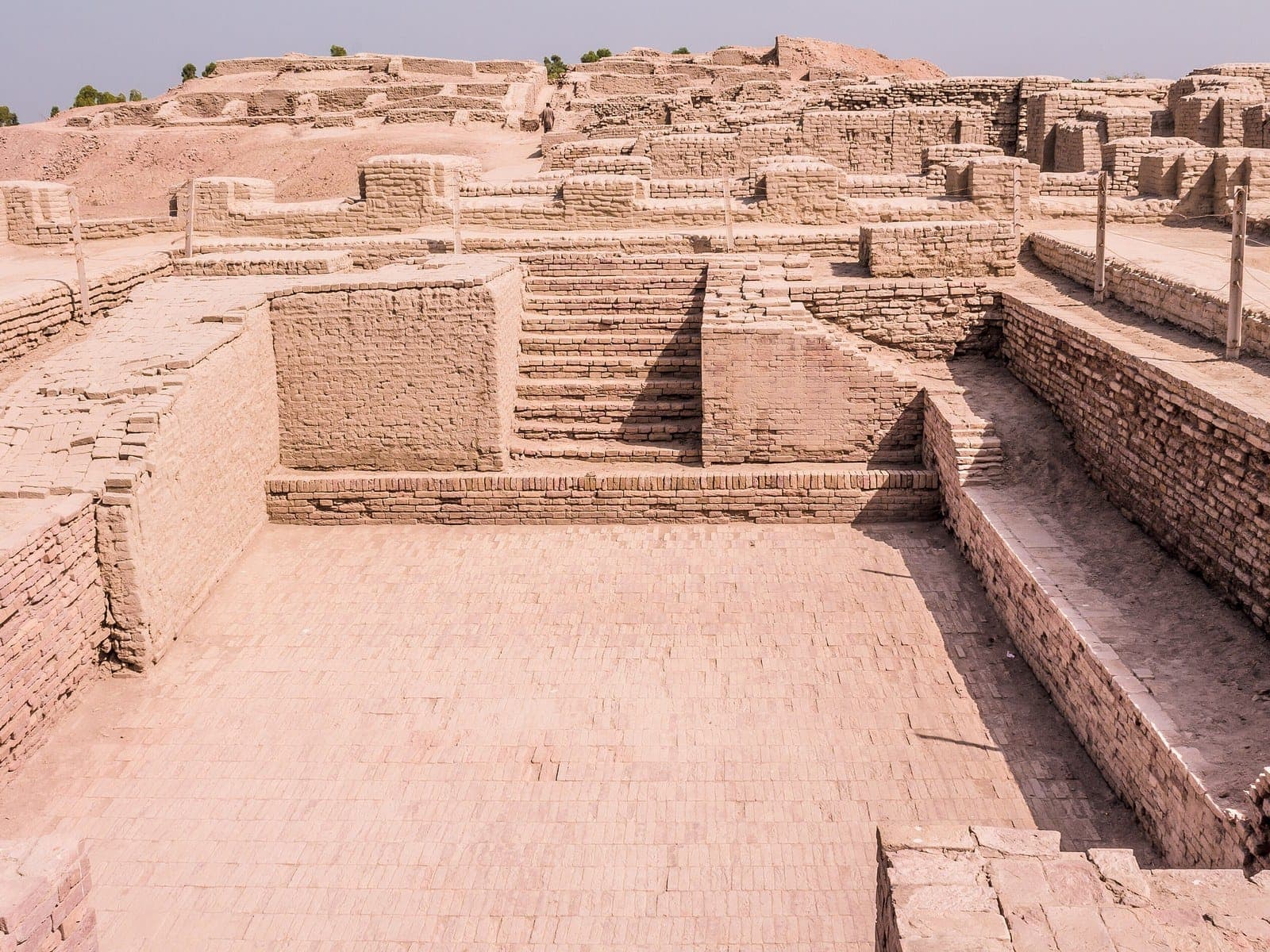 The Great Bath at Mohenjo-daro, a rectangular brick-lined basin with stairs descending into it, among the brick walls of the ancient city.