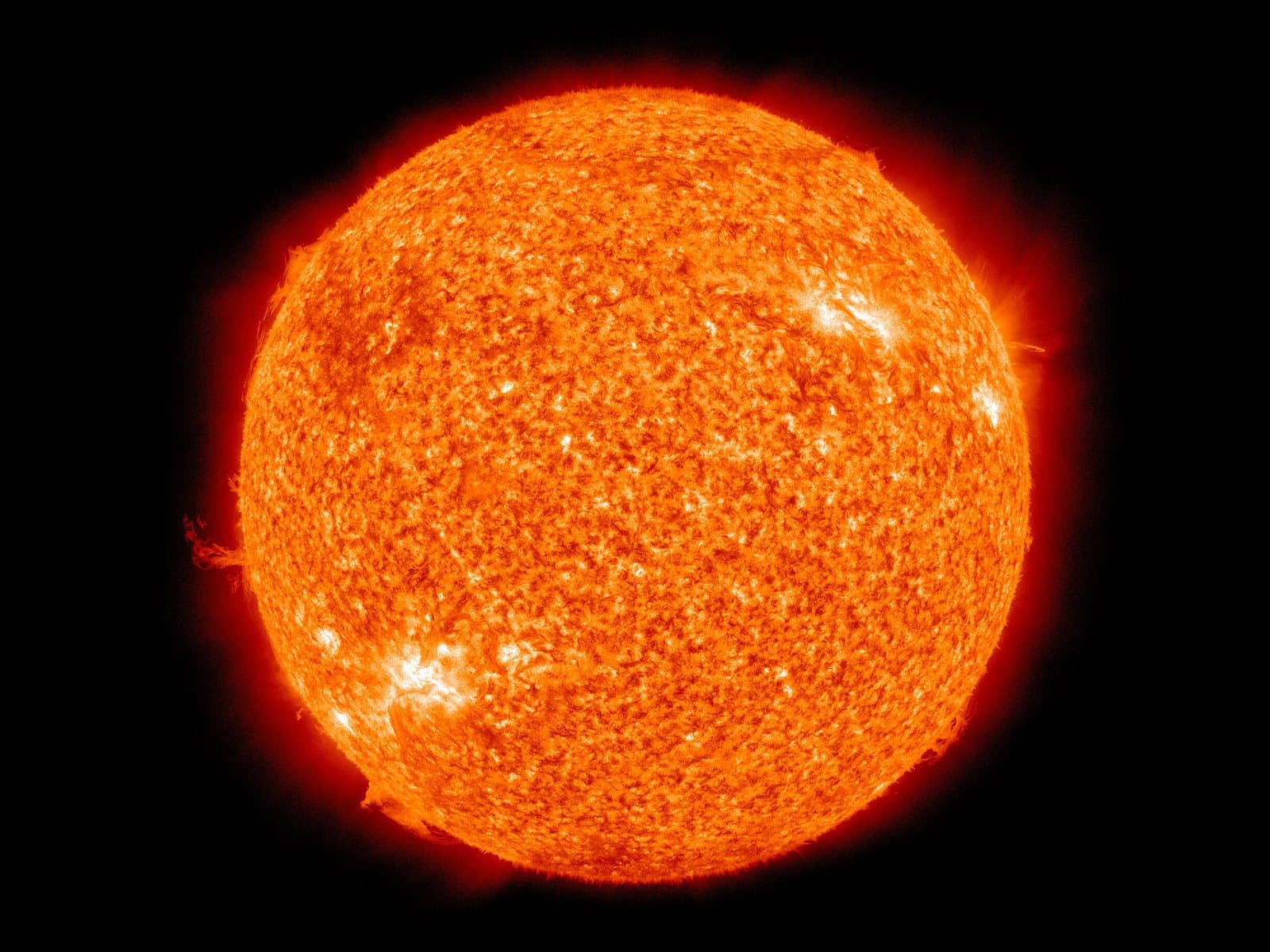 The Sun photographed in extreme ultraviolet light, a bright orange sphere with a textured surface against black space.