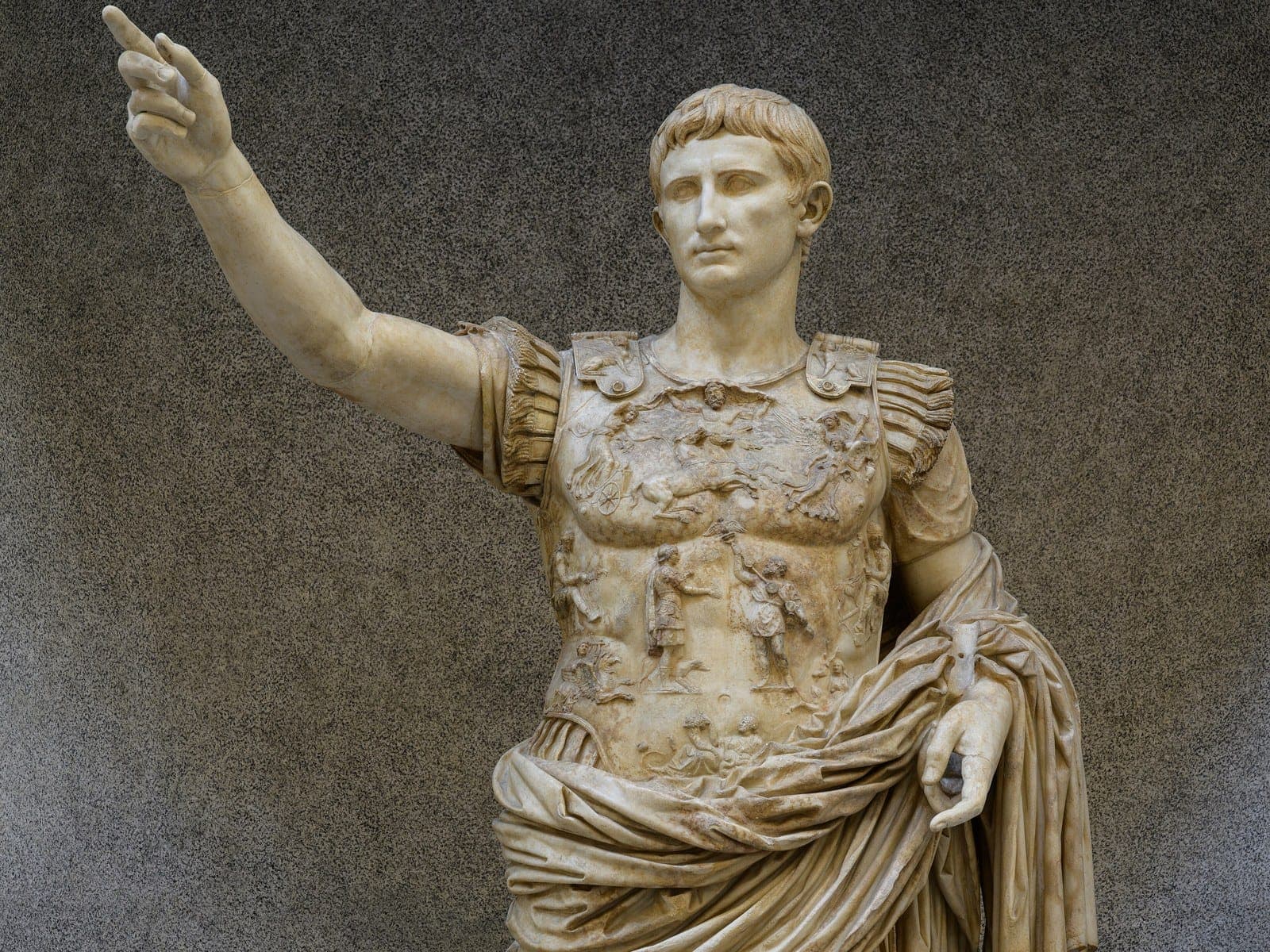 The upper body of the marble statue Augustus of Prima Porta, with his right arm raised and a breastplate carved in relief.